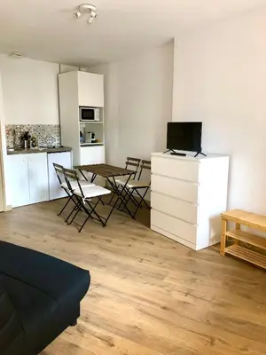 a living room with a table and chairs and a kitchen at Logement neuf, tout confort, au coeur du village in Saint-Didier