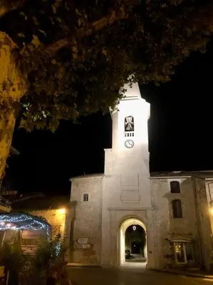 a white building with a clock tower at night at Logement neuf et climatisé, au coeur du village in Saint-Didier