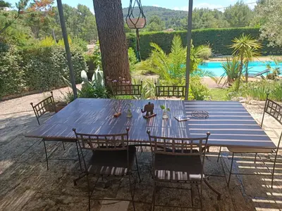 a blue wooden table with chairs and a pool at Villa provençale et ses grands pins in Pernes-les-Fontaines