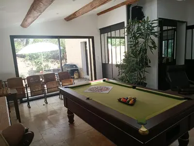 a pool table in a living room with a pool at Villa provençale et ses grands pins in Pernes-les-Fontaines