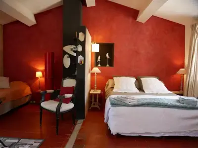 a bedroom with two beds and a red wall at La maison de Muriel in Rustrel