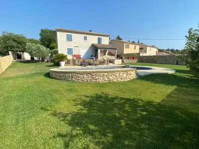 a backyard with a stone retaining wall and a pool at Villa individuelle avec piscine privée proche du Ventoux in Blauvac