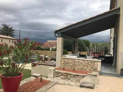 a patio with a stone fireplace and a black awning at Villa individuelle avec piscine privée proche du Ventoux in Blauvac