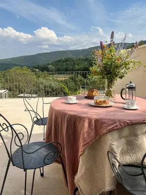 a table with a plate of food and a vase of flowers at La Mirande à Lacoste in Lacoste