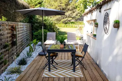 a patio with a table and chairs and an umbrella at LES LODGES TAIZEN, séjour SPA- sans enfants in Saint-Cannat