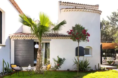 a white house with a palm tree and chairs at LES LODGES TAIZEN, séjour SPA- sans enfants in Saint-Cannat