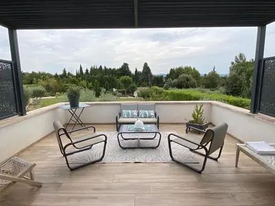 a patio with chairs and a couch on a balcony at Maison avec ses 2 terrasses et sa piscine in Eyragues