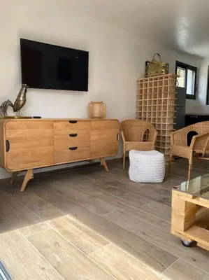 a living room with a tv and a wooden dresser at Maison avec ses 2 terrasses et sa piscine in Eyragues