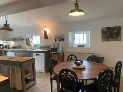 a kitchen with a wooden table and a table and chairs at La Bastide des Chênes Lacoste in Lacoste