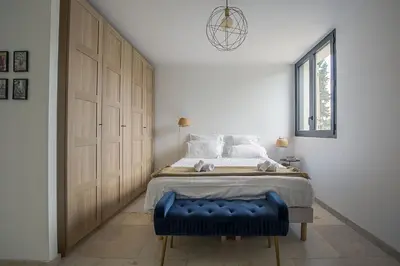 a bedroom with a bed with a blue ottoman next to a door at Mas Etienne Piscine&Nature Saint-Rémy Conciergerie in Saint-Rémy-de-Provence