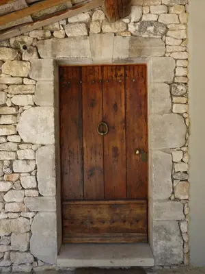 a wooden door in a stone wall at La Bergerie Provencale - Luberon - Provence - villa with heated pool in Roussillon