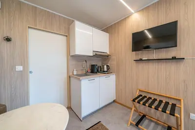 a kitchen with white cabinets and a table and a chair at Le Chant des Pins Lodge & Spa Tour de Keyrié in La Mignarde