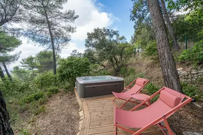 a deck with two chairs and a television on it at Le Chant des Pins Lodge & Spa Tour de Keyrié in La Mignarde