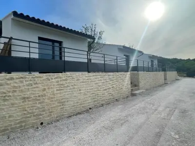 a house with a brick wall and a fence at Noyau & Pepin in Rognes