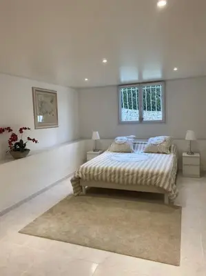 a white bedroom with a bed and two windows at T2 avec jardin et piscine privée in Velaux