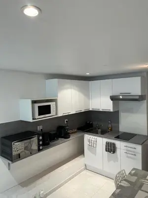 a kitchen with white cabinets and a microwave at T2 avec jardin et piscine privée in Velaux
