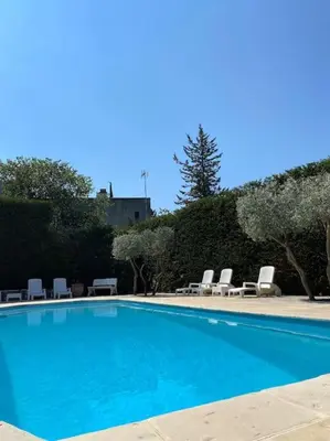 a blue swimming pool with lounge chairs and trees at T2 avec jardin et piscine privée in Velaux
