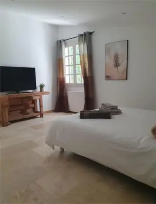 a bedroom with a bed and a flat screen tv at Mas du Tilleul - LUBERON in Cadenet