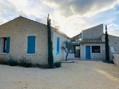 a house with blue shutters on the side of it at Mas de charme avec piscine au coeur des Alpilles in Eygalières