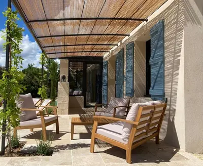 a patio with two chairs and a wooden pergola at Mas de charme avec piscine au coeur des Alpilles in Eygalières
