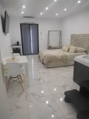 a white bedroom with a bed and a table and a tableablish at Spa NESSA in Saint-Andiol