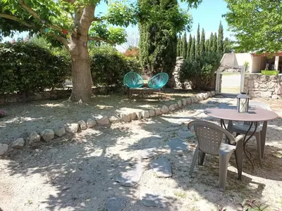 a patio with two chairs and a table and a tree at Maisonnette rénovée en campagne in Velleron