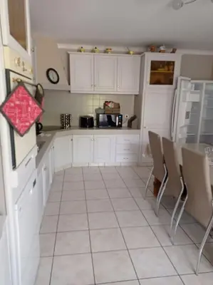 a kitchen with white cabinets and a table and chairs at maison piscine privée Robion Luberon idéal famille in Robion en Luberon
