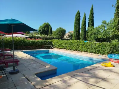 a swimming pool in a yard with an umbrella at maison piscine privée Robion Luberon idéal famille in Robion en Luberon