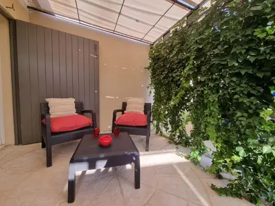 two chairs and a table in front of a green wall at Ma Charmante Maison En Provence in Lançon-Provence