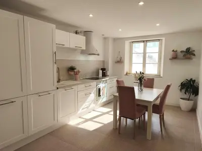 a kitchen with white cabinets and a table with chairs at Appartement fontaine de Vaucluse in Fontaine-de-Vaucluse