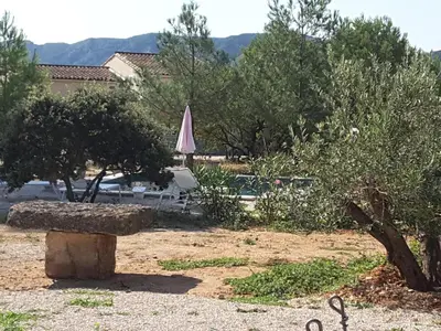 a stone bench in a yard with an umbrella at mas clair de lune in Saint-Rémy-de-Provence