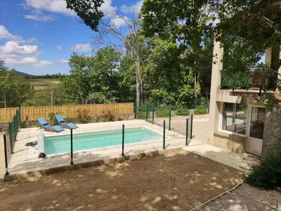 a swimming pool with two chairs next to a house at Maison confortable à Ansouis dans Le Luberon in Ansouis