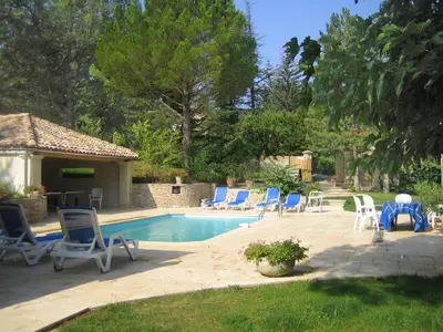 a swimming pool with blue chairs and a group at Le grand Liodrey in Céreste