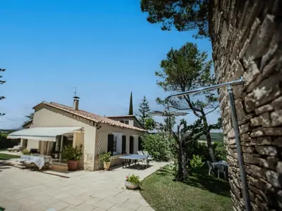 a house with a stone wall and a patio at Le grand Liodrey in Céreste