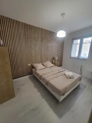 a bedroom with a bed and a wooden wall at Appartement Cosy centre ville in LʼIsle-sur-la-Sorgue