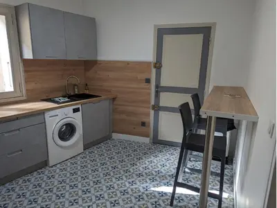 a small kitchen with a washing machine and a table at Appartement Cosy centre ville in LʼIsle-sur-la-Sorgue