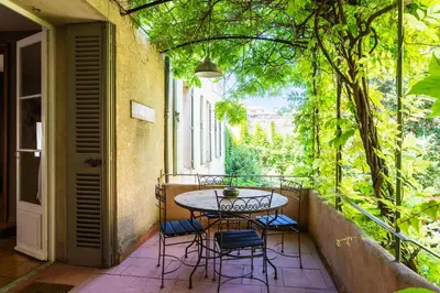 a table and chairs on a balcony with trees at Le Gîte du Carmel in Carpentras