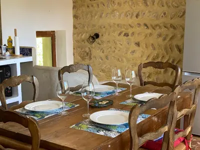 a wooden table with plates and wine glasses on it at Mazet au pied des Alpilles, avec Piscine & Pétanque in Salon-de-Provence