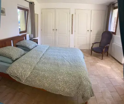 a bedroom with a large bed and a chair at Mazet au pied des Alpilles, avec Piscine & Pétanque in Salon-de-Provence