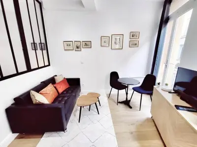 a living room with a black couch and a table at Le Boulegon by La Familia in Aix-en-Provence