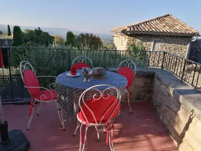 a table with red chairs on a patio with a view at Chambre d'hôte in Crillon-le-Brave