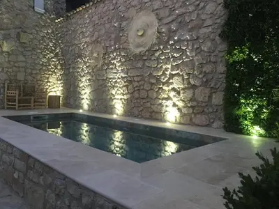 a swimming pool in front of a stone wall at Maison en pierre avec piscine, 6 couchages, située au cœur de Mallemort, Provence. - FR-1-658-25 in Mallemort