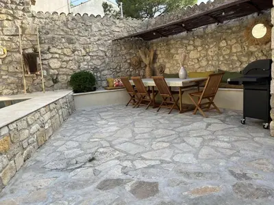 a patio with a table and chairs and a stone wall at Maison en pierre avec piscine, 6 couchages, située au cœur de Mallemort, Provence. - FR-1-658-25 in Mallemort