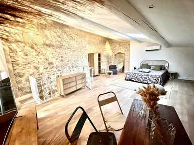a living room with a bed and a stone wall at Maison en pierre avec piscine, 6 couchages, située au cœur de Mallemort, Provence. - FR-1-658-25 in Mallemort