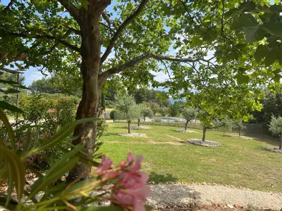 a park with trees and grass and pink flowers at Proche Roussillon, La villa rouge Luberon, piscine chauffée, climatisation et vue Luberon in Gargas