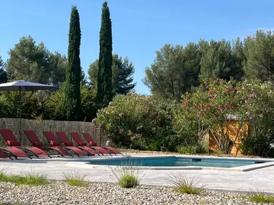 a swimming pool with lounge chairs and an umbrella at Proche Roussillon, La villa rouge Luberon, piscine chauffée, climatisation et vue Luberon in Gargas