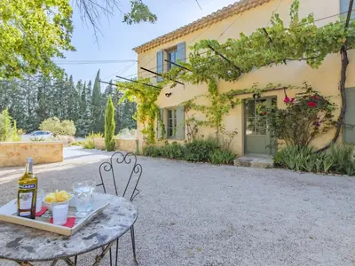 a table with a bottle of wine next to a building at Holiday Home Le Mas de Marius by Interhome in Cavaillon