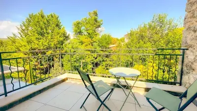 a balcony with chairs and a table and trees at Les Iris in Céreste
