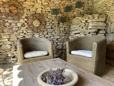 two chairs and a table in front of a stone wall at La Villa Baronnette in Cabrières-dʼAvignon