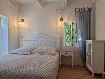a bedroom with a white bed and a window at Mas Cerisiers in Saint-Martin-de-Castillon